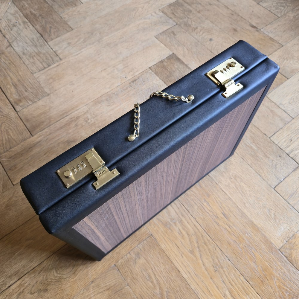 Lastoria in three-quarter view, with black leather, a framed panel and metal fittings.