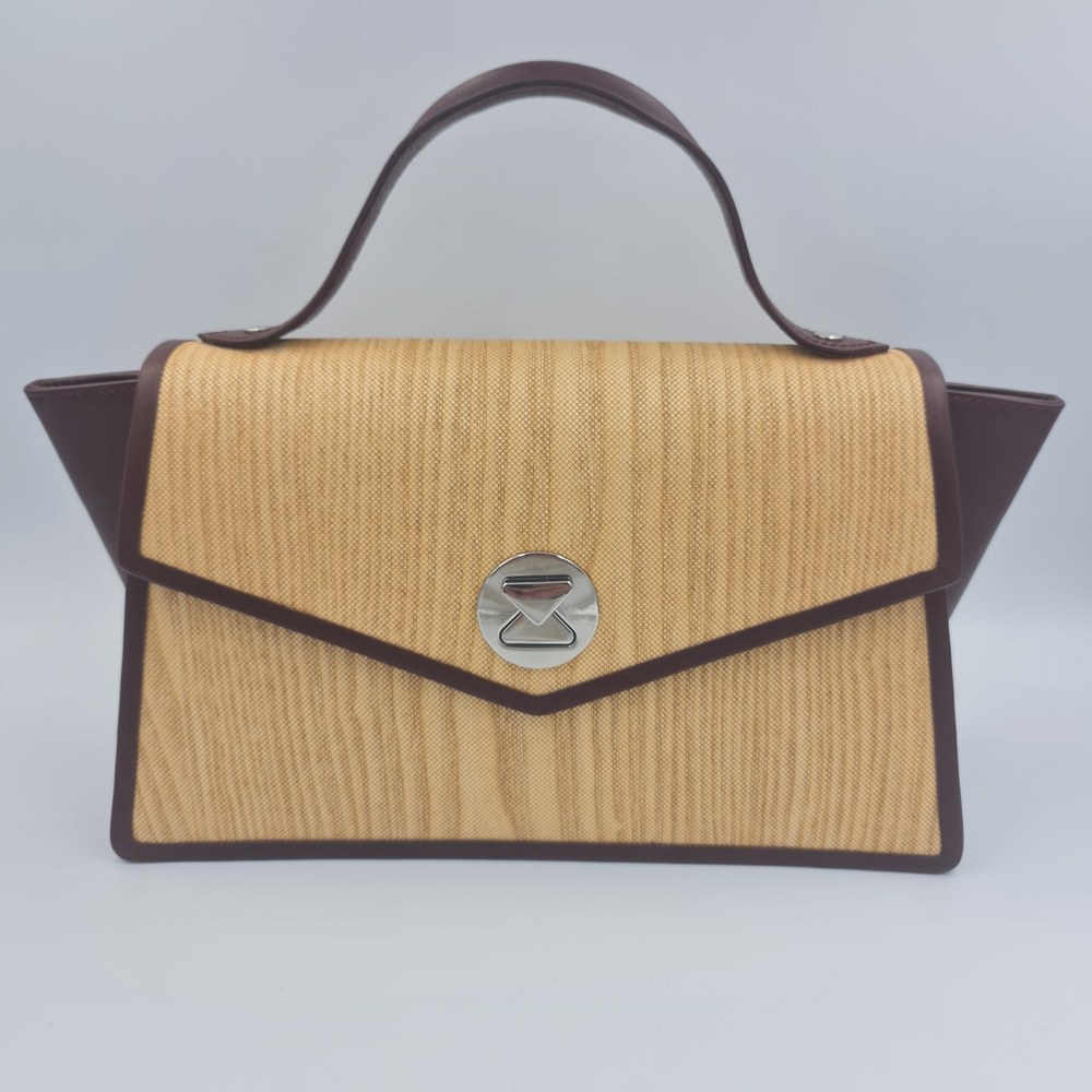 Nuo Elegance handbag seen from the front, with a golden textured panel, dark burgundy edging and a circular silver clasp.