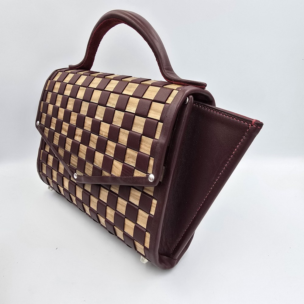 Vinea handbag in three-quarter view, showing the checked front, curved handle and burgundy side panel.