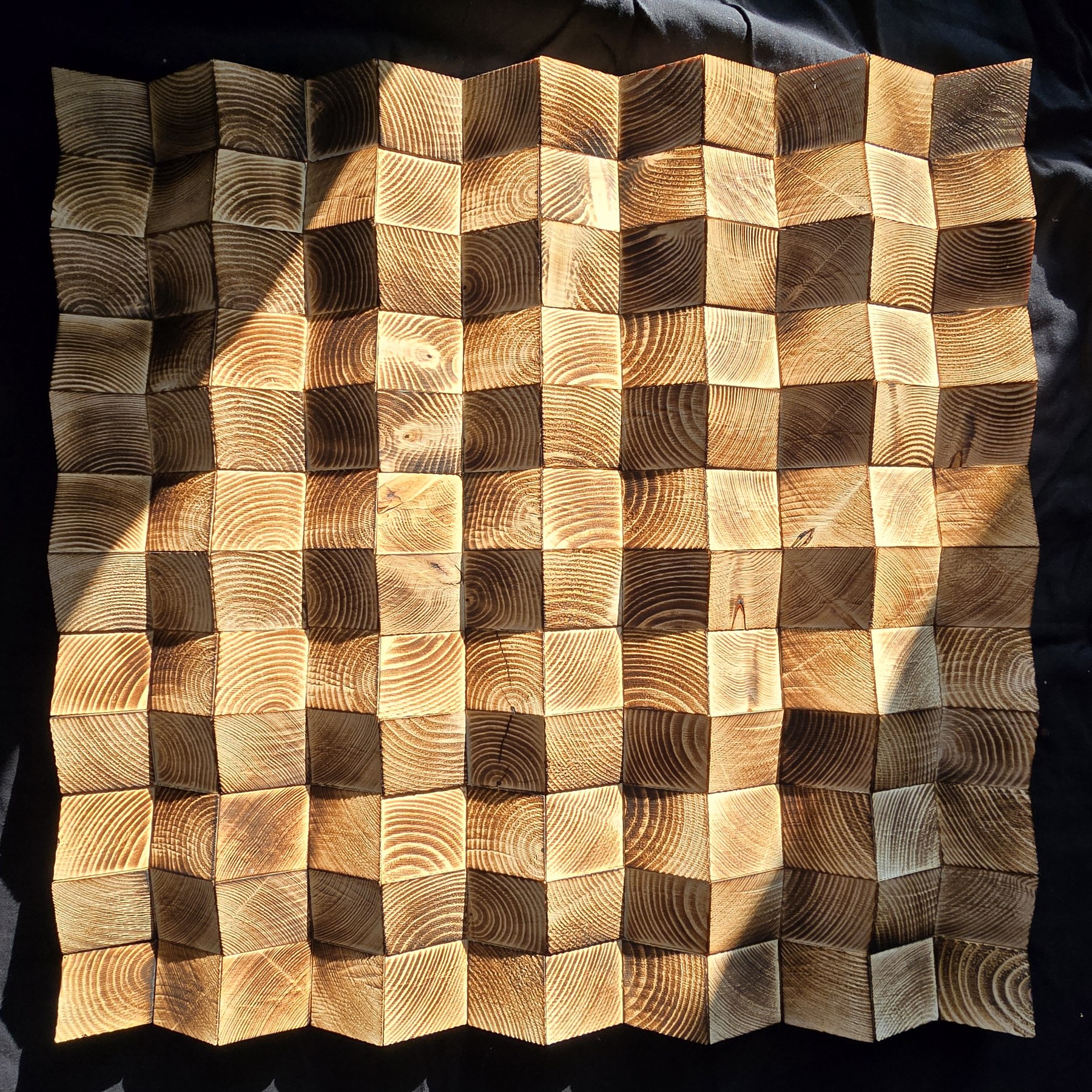Light and shadow across a wooden wall mosaic
